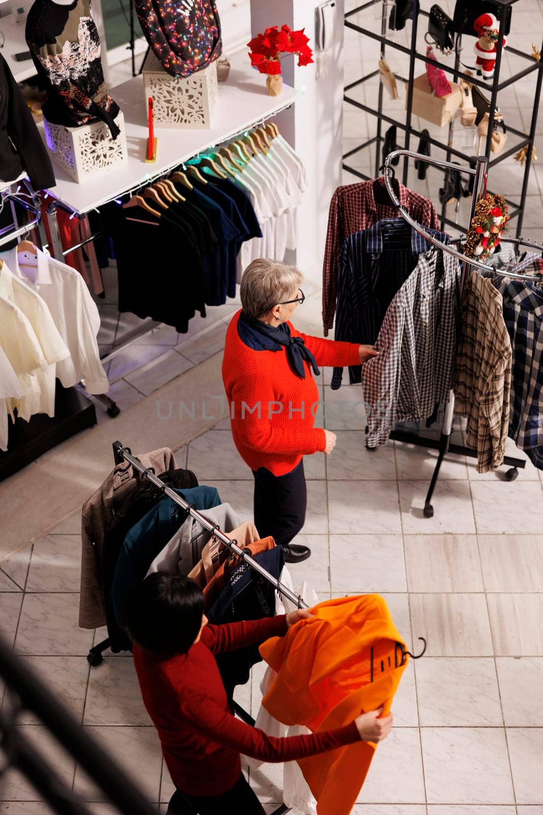 Multiple clients looking for xmas gifts and festive attire, people making preparations for christmas eve festivities and tradition. Retail store customers shopping for clothes during december season.