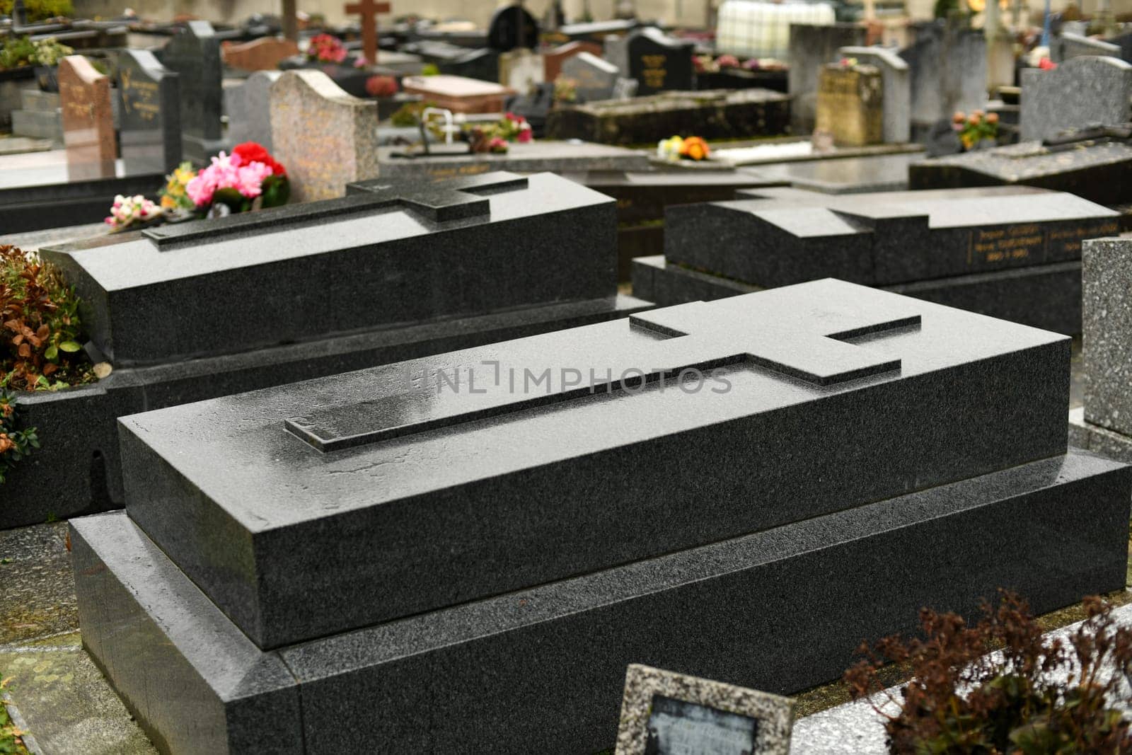 Cross on a black marble slab on a grave in a cemetery by Godi