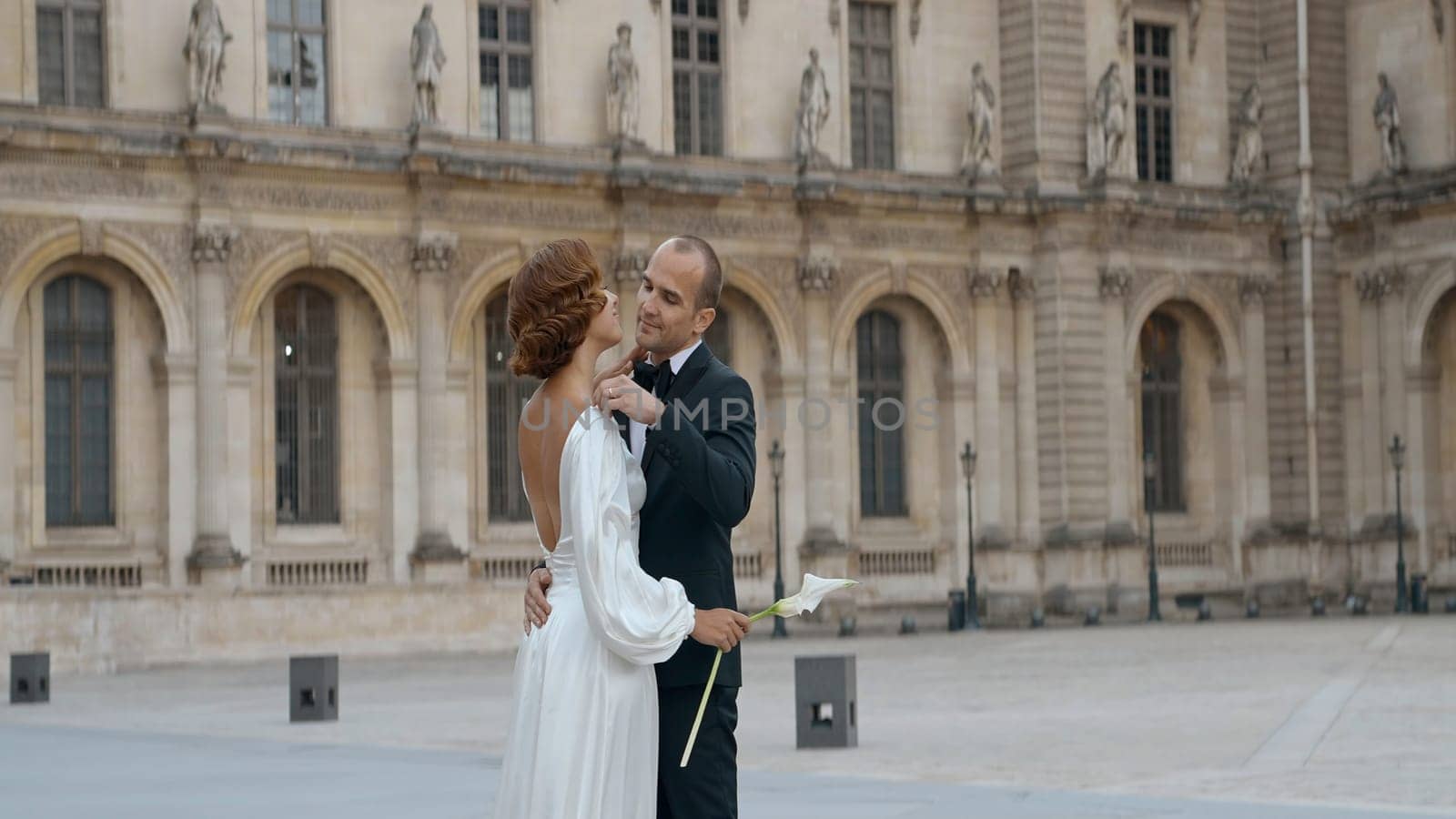 Beautiful young bride and groom walking outdoors on the medieval castle territory. Action. Creative wedding celebration