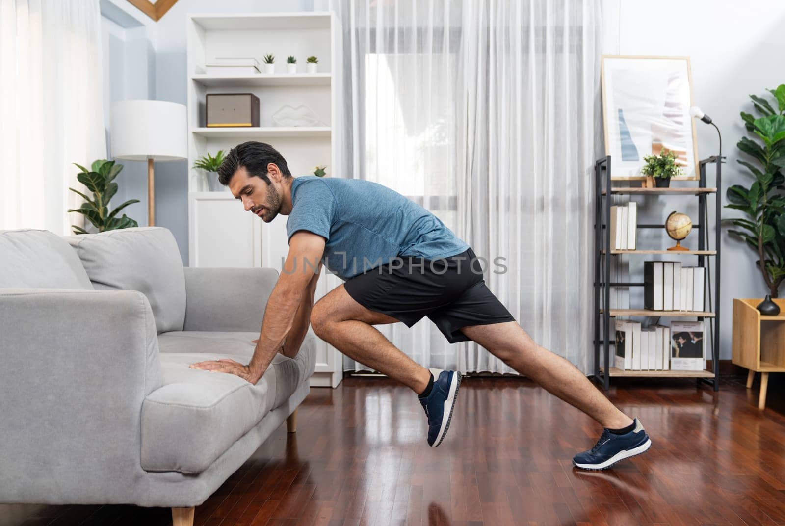 Athletic body and active sporty man using furniture for gaiety home exercise. by biancoblue