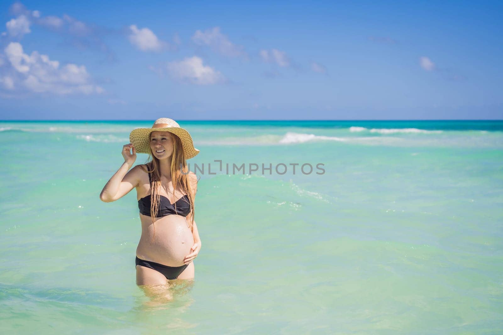 Radiant and expecting, a pregnant woman stands on a pristine snow-white tropical beach, celebrating the miracle of life against a backdrop of natural beauty by galitskaya