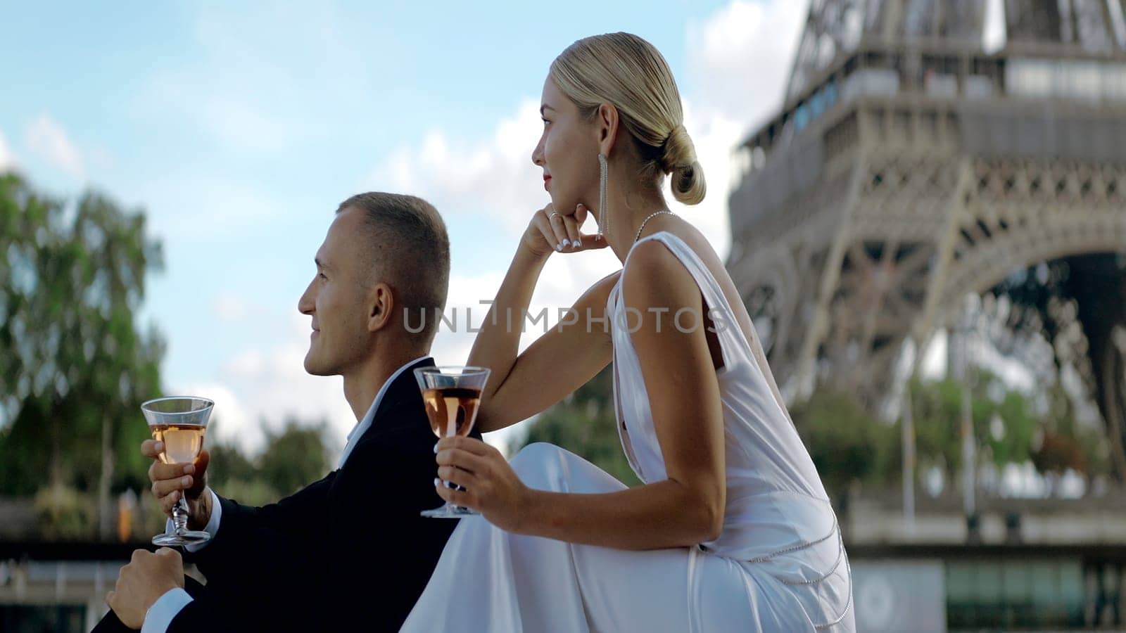 Chatting young couple on vacation. Action. A beautiful elegant girl in a white dress sits with her man and communicates against the background of sights in the summer. by Mediawhalestock