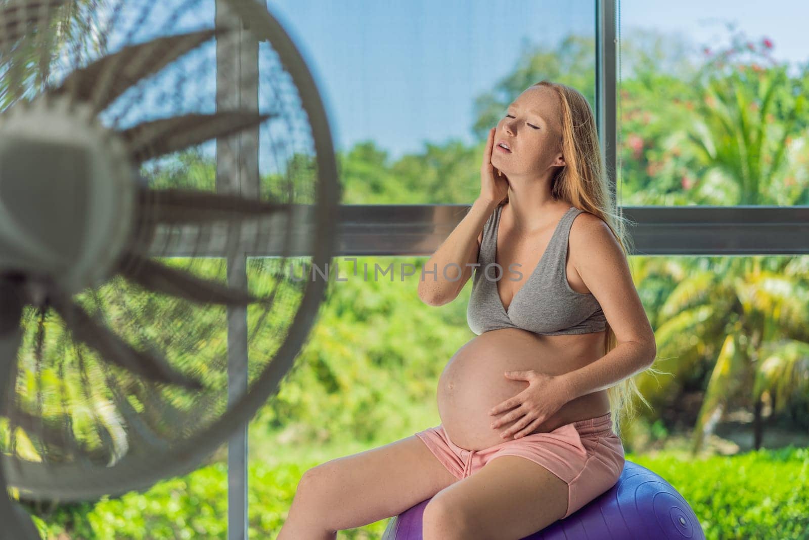 A pregnant woman seeks relief from an abnormal heatwave by using a fan, ensuring her comfort and well-being during sweltering conditions.