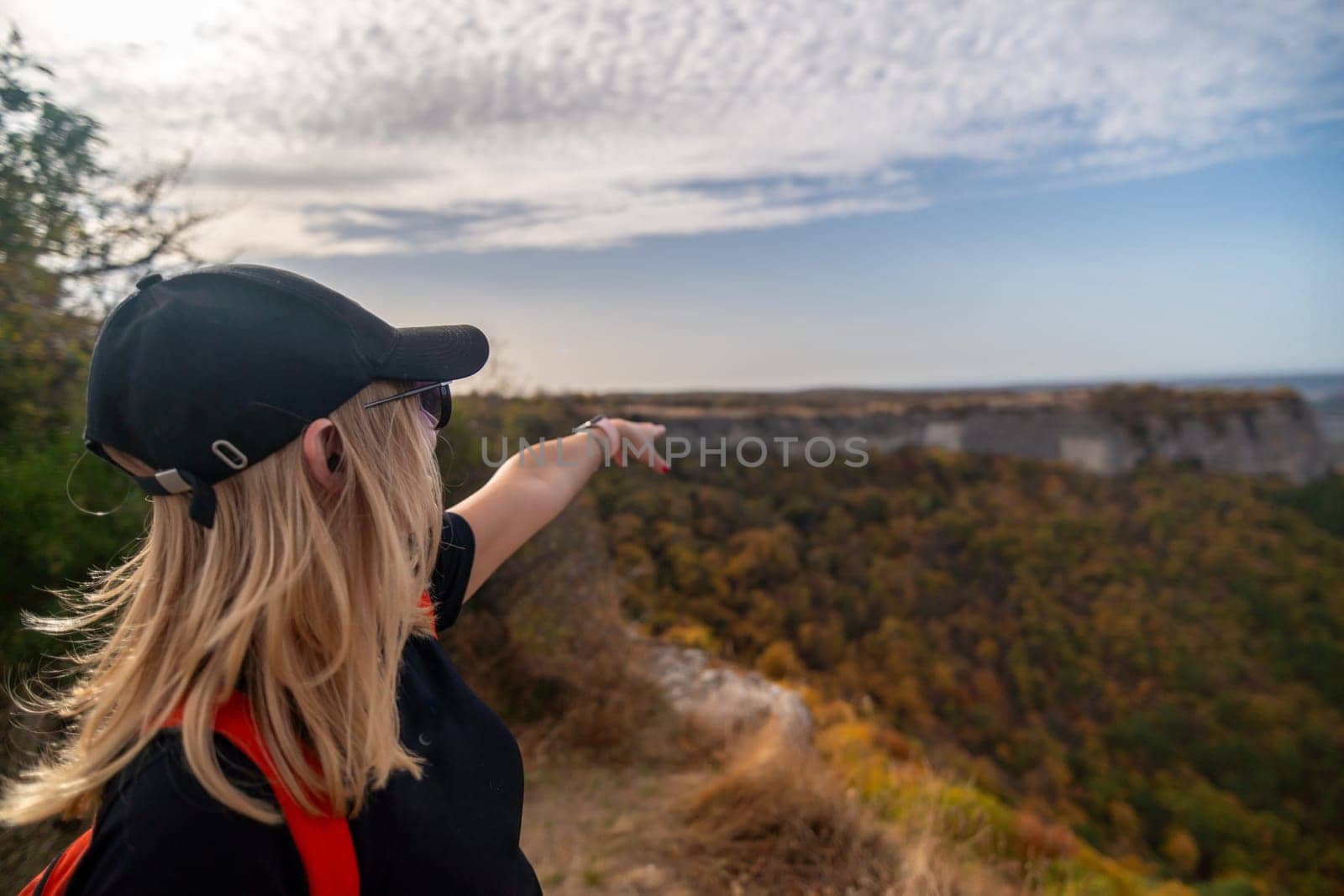 woman on mountain peak looking in beautiful mountain valley in autumn. Landscape with sporty young woman, blu sky in fall. Hiking. Nature.