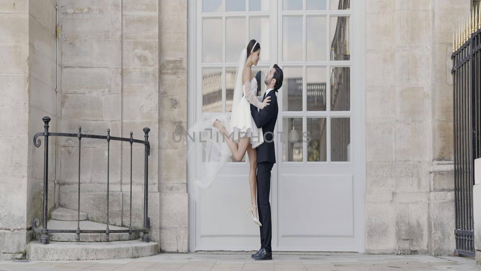 Beautiful date photo shoot. Action.A young girl in a short dress and a man lifting her and sitting in front of the architecture. High quality 4k footage