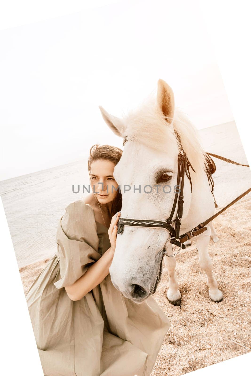 A woman in a dress stands next to a white horse on a beach, with the blue sky and sea in the background