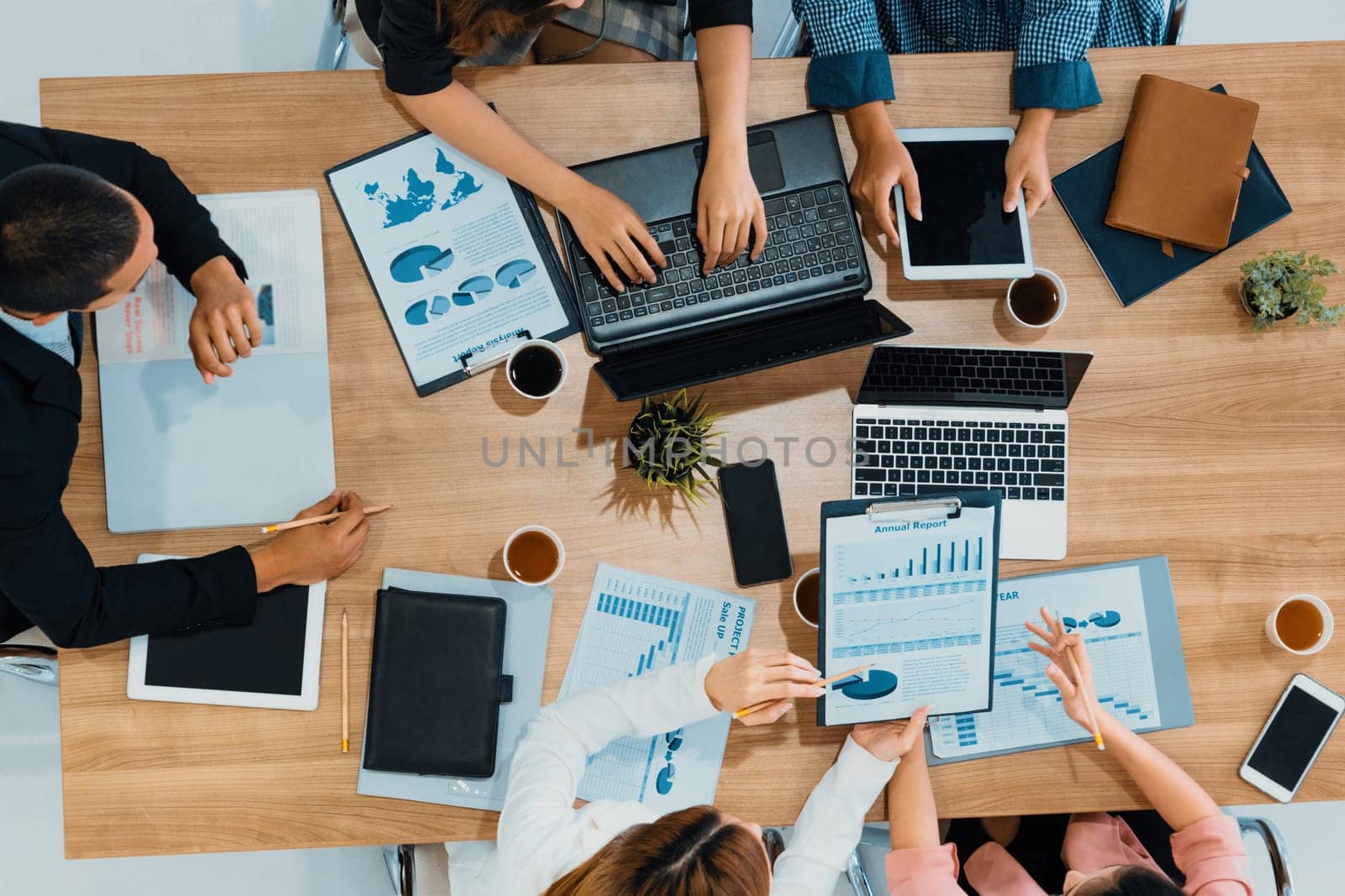 Top view of businessman executive in group meeting with other businessmen and businesswomen in modern office with laptop computer, coffee and document on table. People corporate business team uds