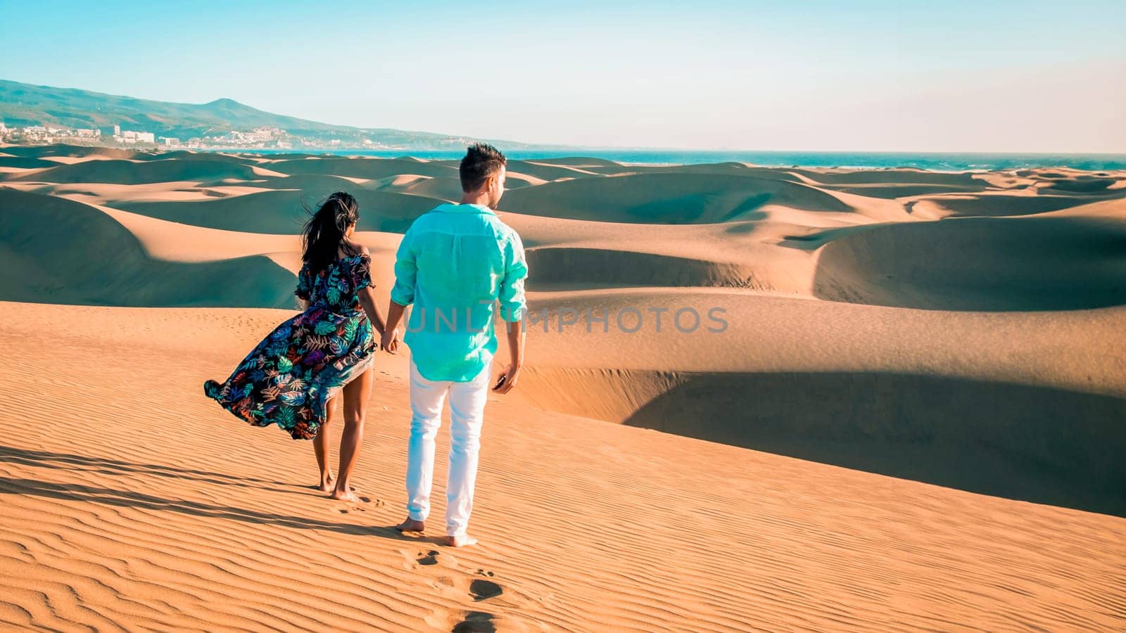 couple walking at the beach of Maspalomas Gran Canaria Spain, men and woman at the dunes desert of Maspalomas Spain Europe in the morning sun