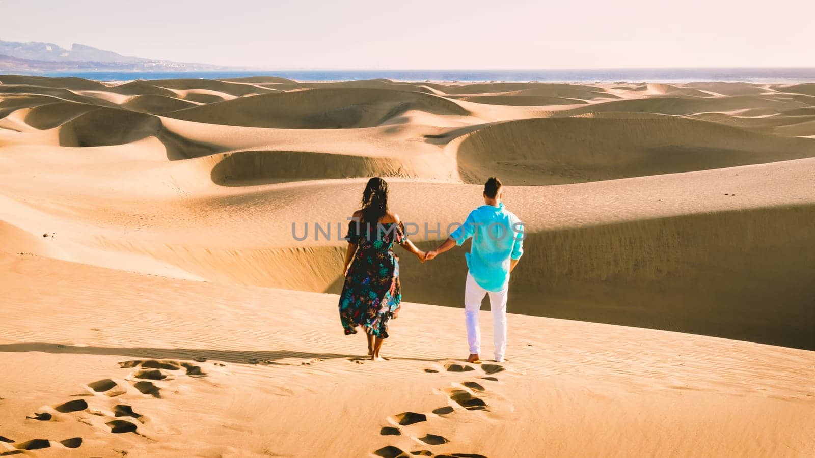 couple walking at the beach of Maspalomas Gran Canaria Spain, men, and woman at the sand dunes desert of Maspalomas Gran Canaria