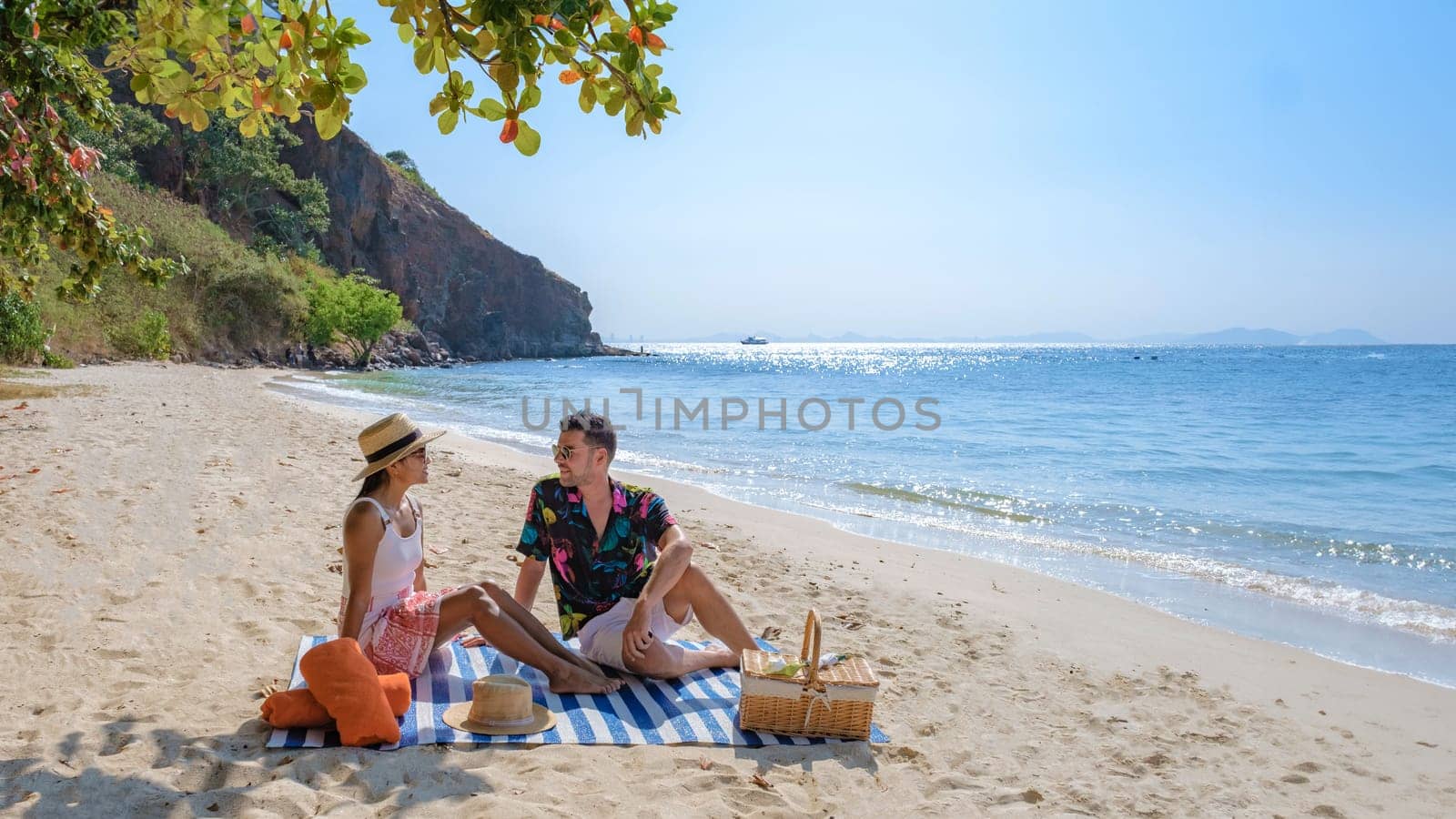 Koh Larn Island near Pattaya Thailand, a couple of men and women picnic on the beach of the tropical Island of Koh Larn Thailand, a white beach with a clear water ocean.