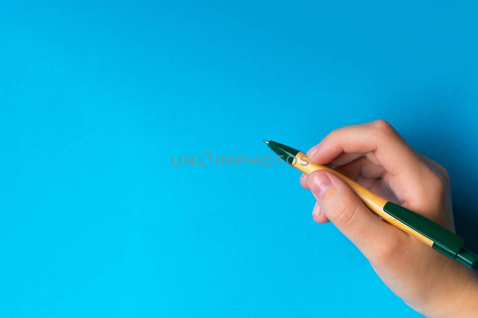 Children hand with pen write on a blue white background. Writing hand.