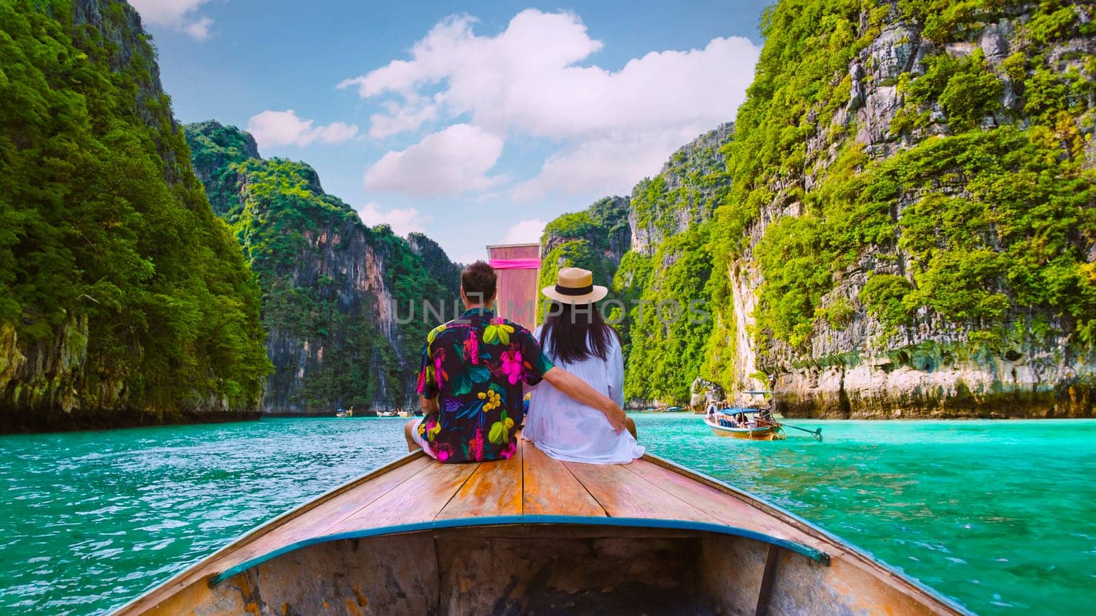 Couple in front of Longtail boat at the lagoon of Koh Phi Phi Thailand during vacation. green blue turqouse colored ocean of Koh Phi Phi Thailand