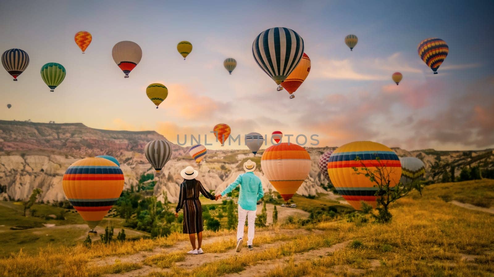 Cappadocia Turkey during sunrise, a couple mid age men and women on vacation in the hills of Goreme Cappadocia Turkey, men and woman looking sunrise with hot air balloons in Cappadocia Turkey