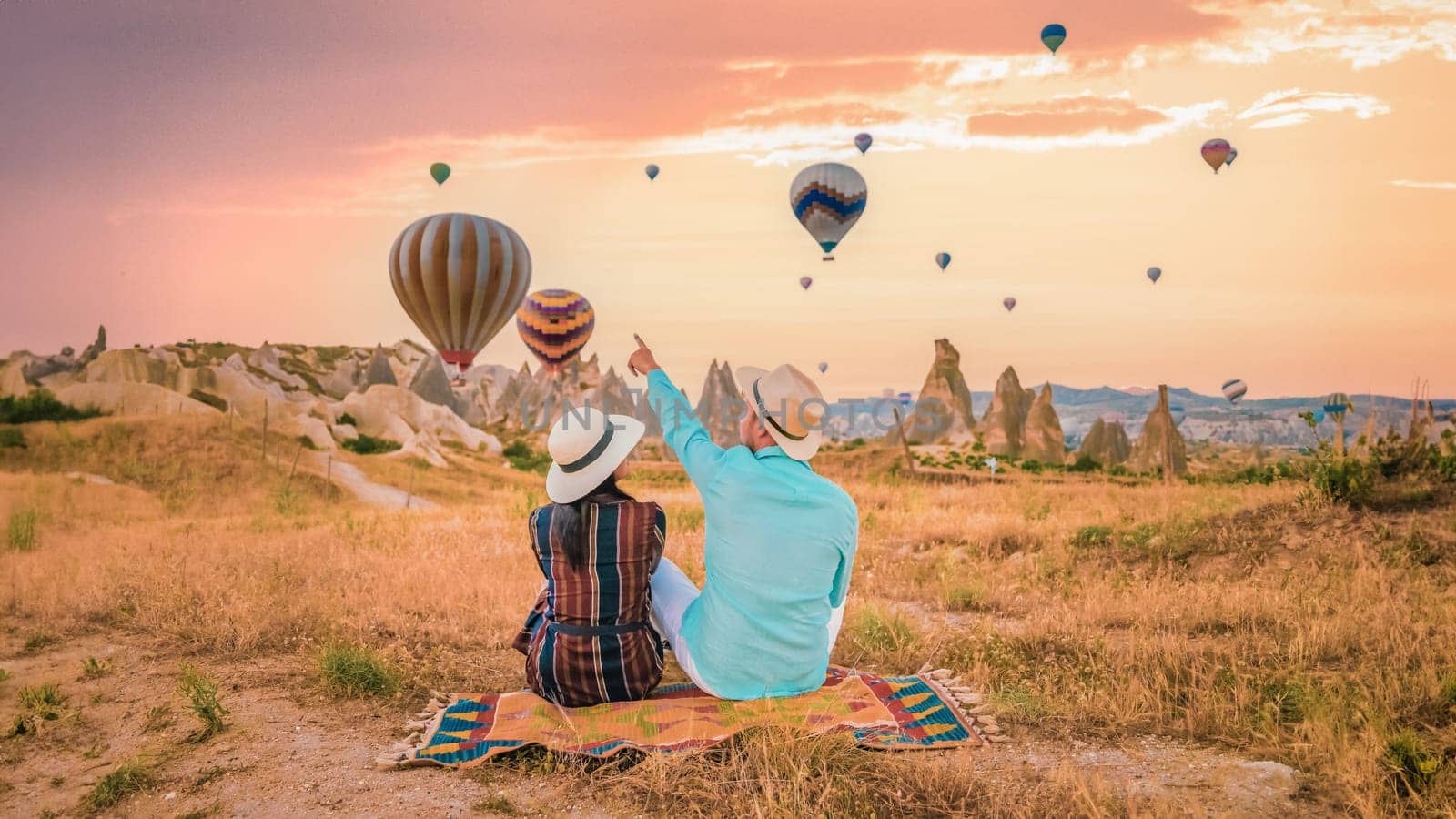 Cappadocia Turkey during sunrise, a couple mid age men and women on vacation in the hills of Goreme Cappadocia Turkey, men and woman looking sunrise with hot air balloons in Cappadocia Turkey holiday