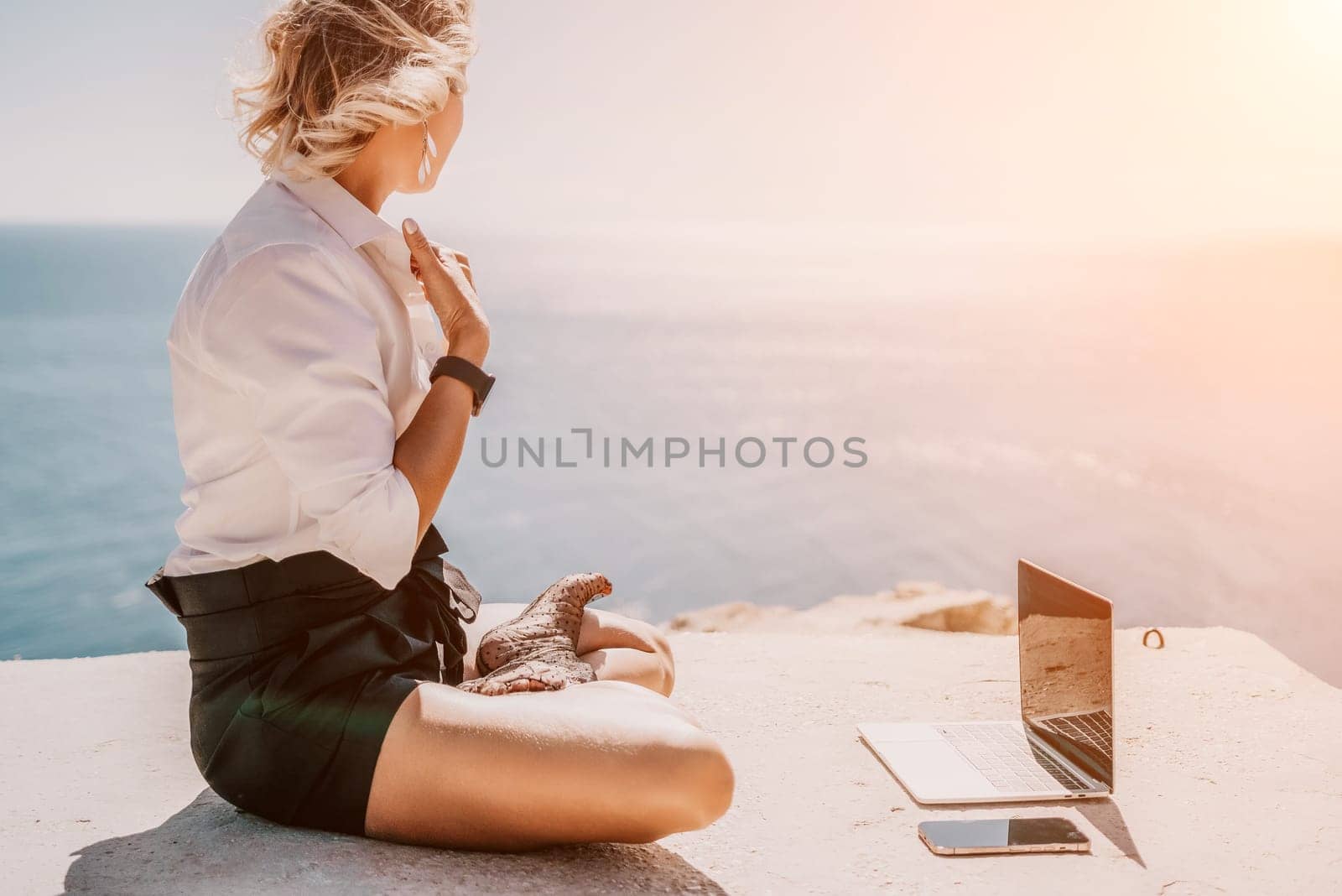 Happy girl doing yoga with laptop working at the beach. beautiful and calm business woman sitting with a laptop in a summer cafe in the lotus position meditating and relaxing. freelance girl remote work beach paradise