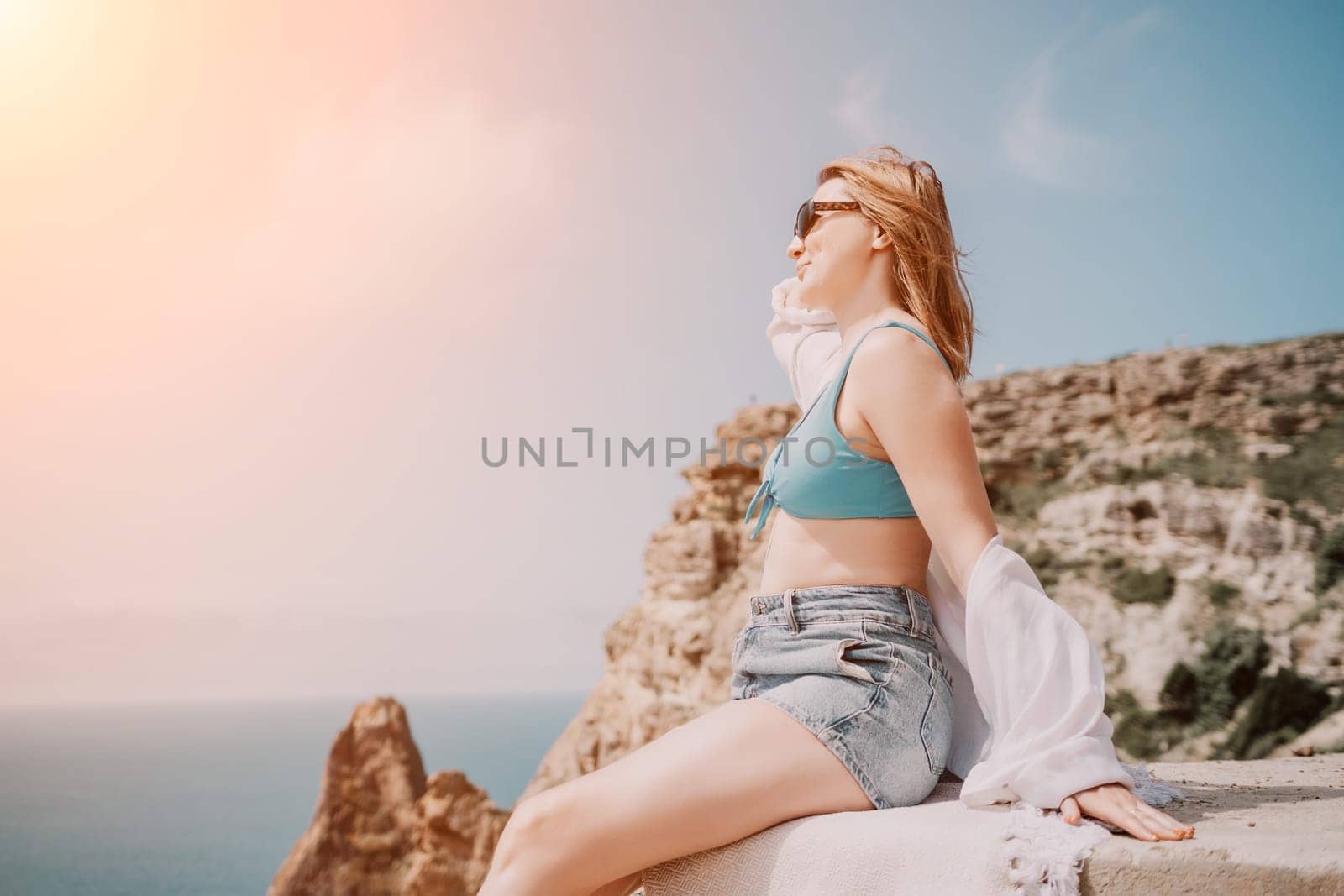 Woman summer travel sea. Happy tourist in sunglasses enjoy taking picture outdoors for memories. Woman traveler posing on beach at sea surrounded by volcanic rocks, sharing travel adventure journey by panophotograph