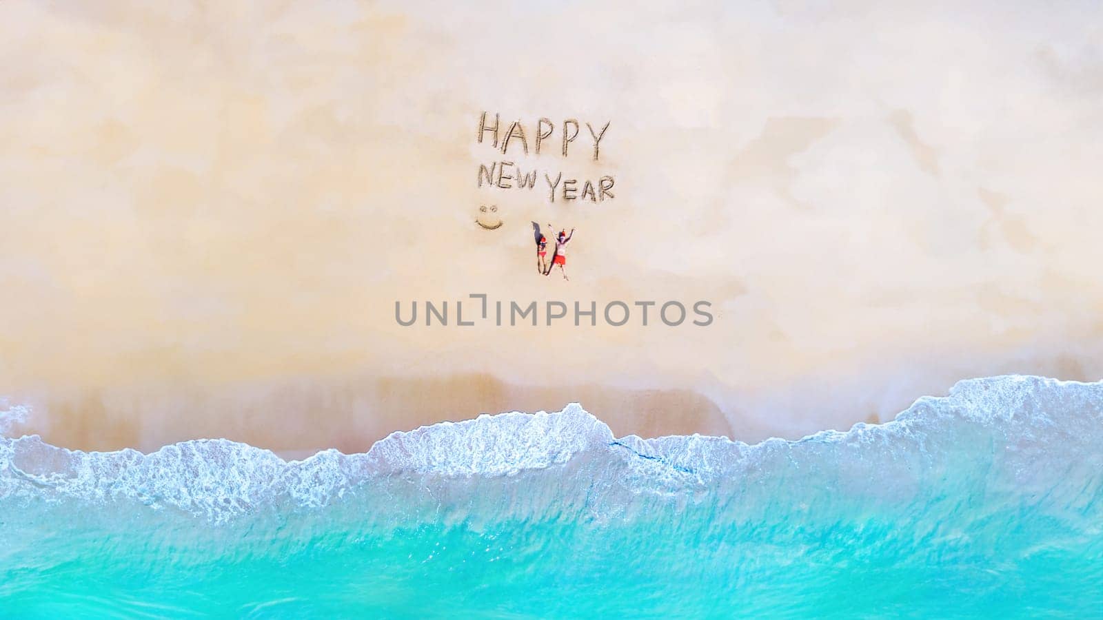 a couple on the beach with a happy new year sign by fokkebok