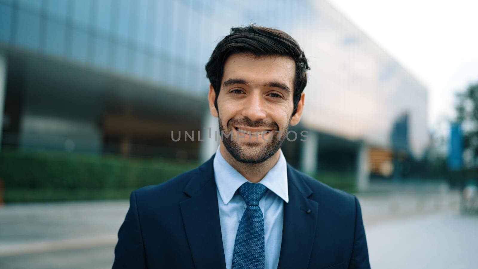 Portrait of business man looking at camera while standing at building. Exultant. by biancoblue