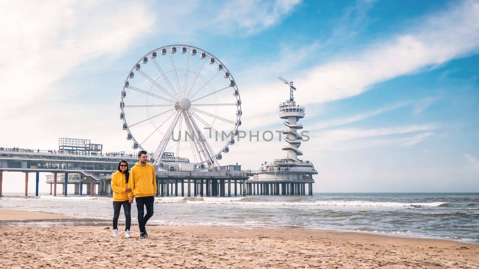 a couple of men and woman on the beach of Scheveningen Netherlands during Spring, The Ferris Wheel at The Pier at Scheveningen in the Netherlands, Sunny spring day at the beach of Holland