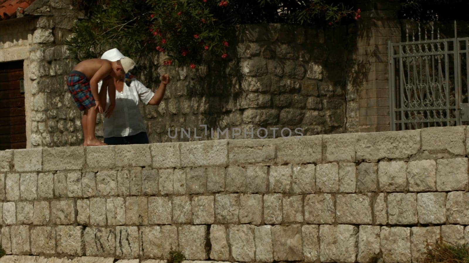 A walking family in the summer. Creative. Grandmother and grandson walk and climb the roads with the sun shining brightly. by Mediawhalestock