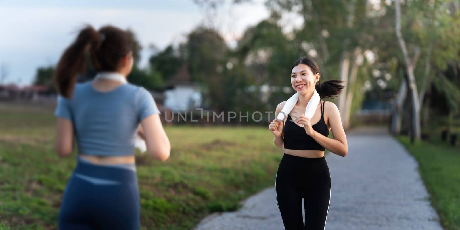 Jogging woman running in park on beautiful day off. Sport fitness model of asian ethnicity training outdoor for marathon.