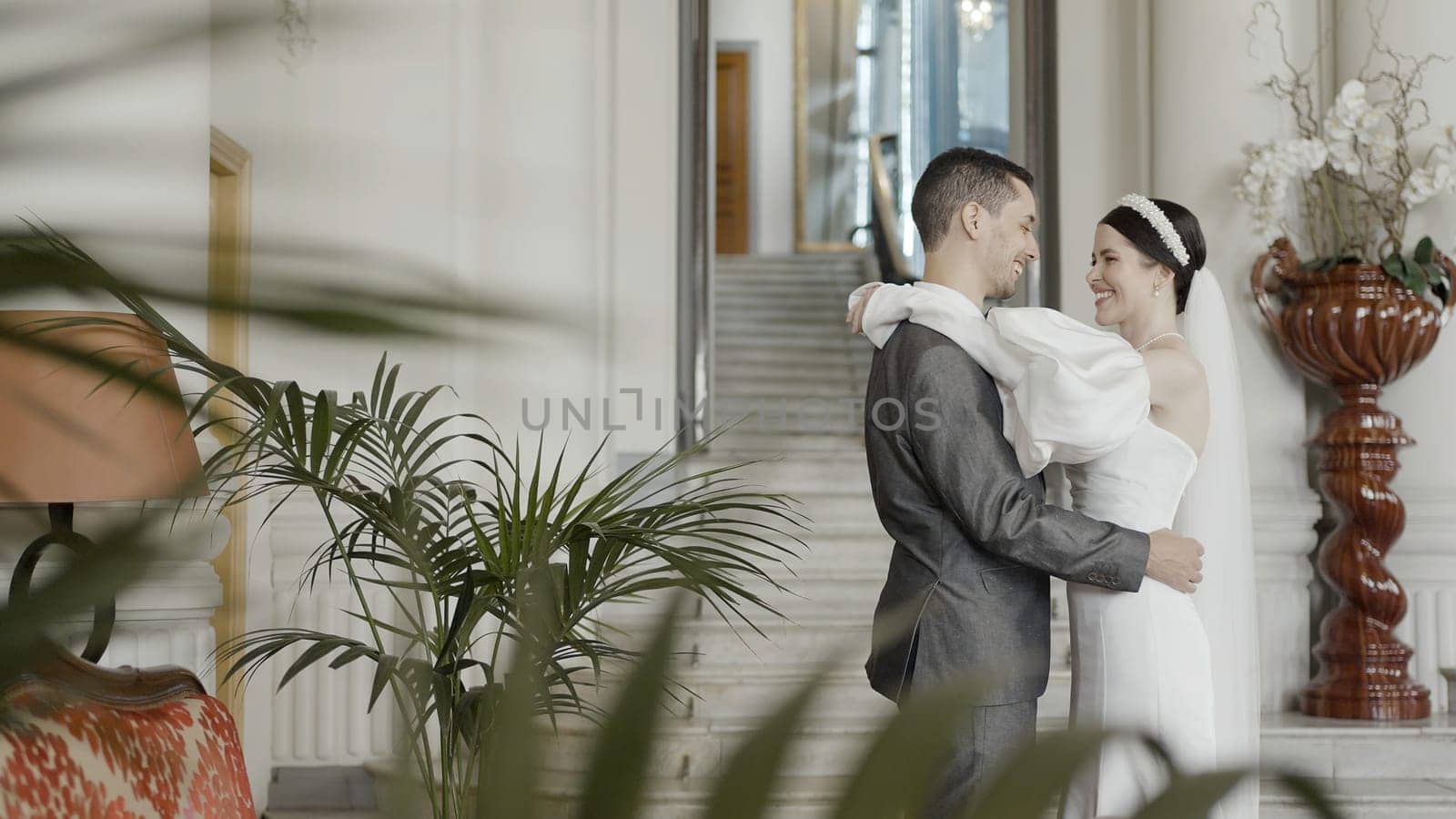 A girl in a beautiful snow- white dress with a bouquet in her hands and a grrom in official suit. Action. A wonderful touching moment of wedding