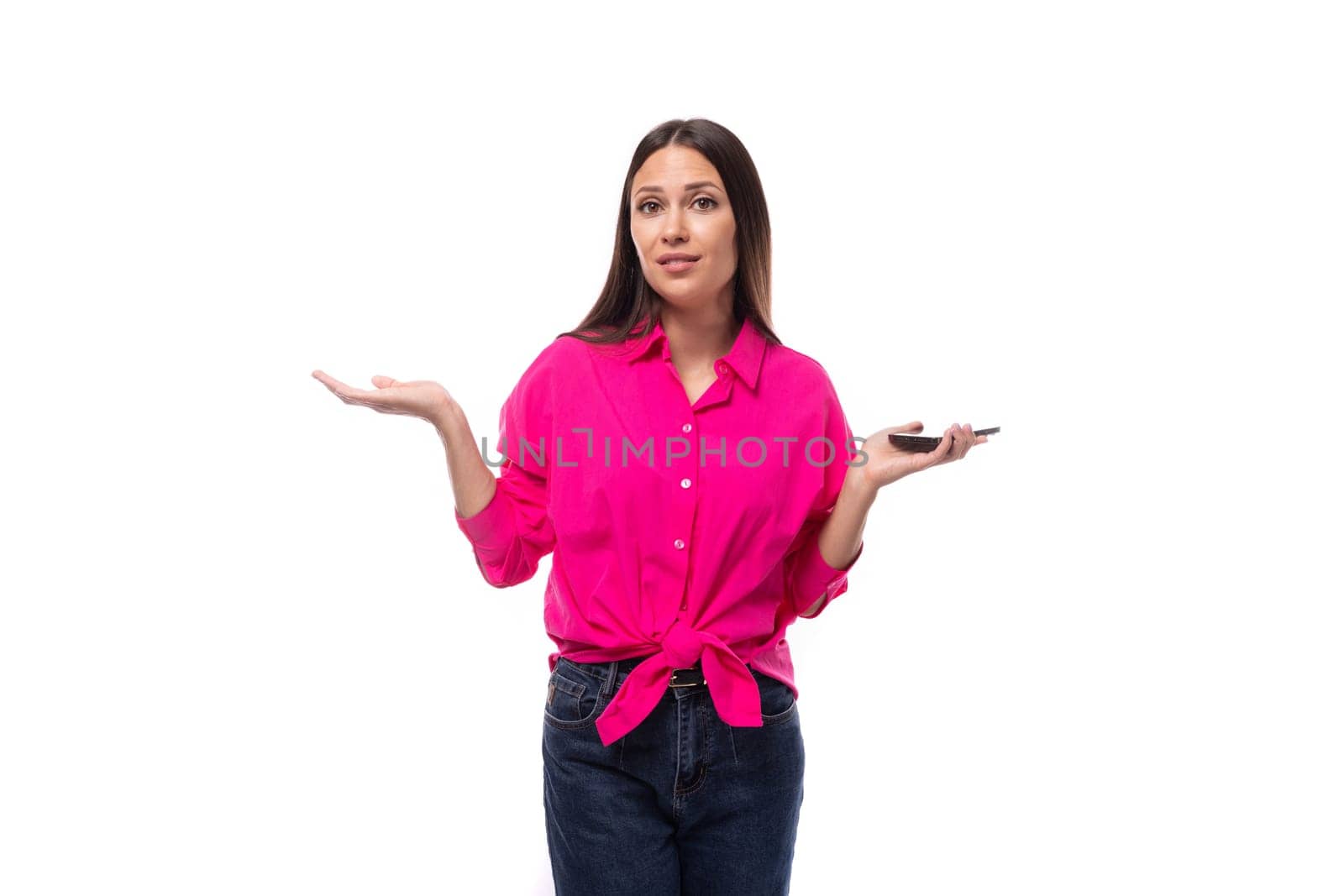 fashionable slim young employee office woman dressed in a pink shirt spread her hands holding a smartphone.