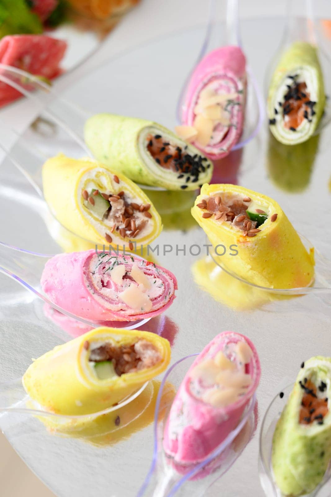 Cheese appetizer in rolls on small disposable spoons, roll in purple and yellow colors.