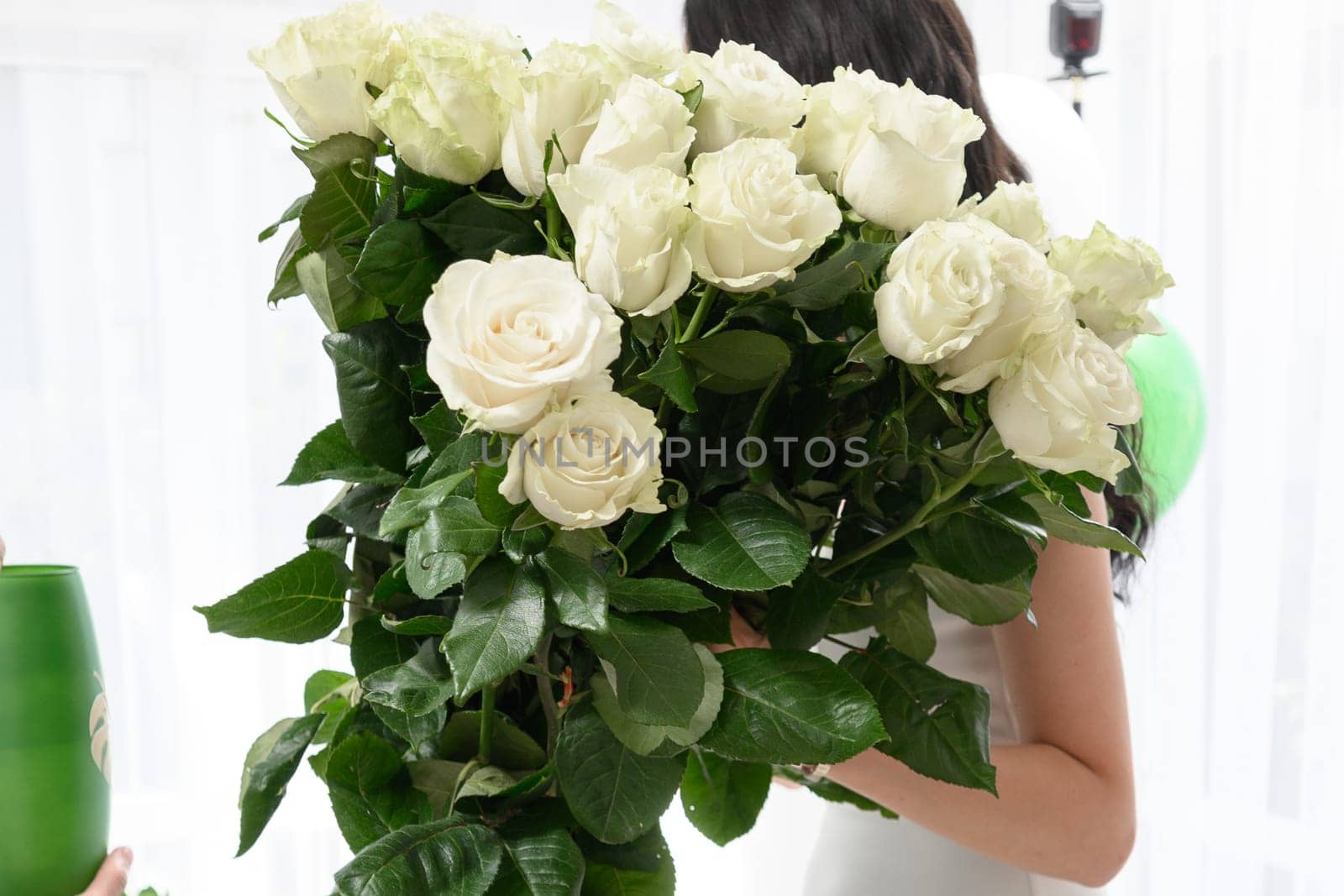 The girl is holding a large bouquet of white roses, a bouquet of fresh roses.