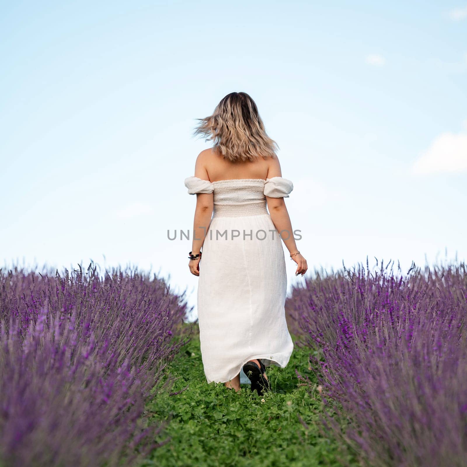 A beautiful girl walks in a white dress in a lavender field, aromatherapy in a lavender field.