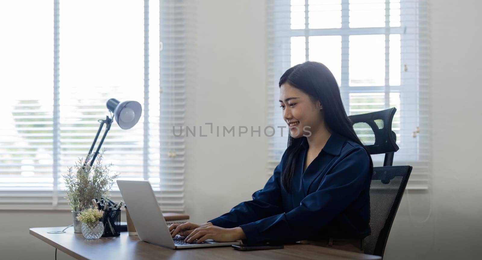 Professional businesswoman working at her home via laptop, young female manager using computer laptop while sitting on desk, work process concept.