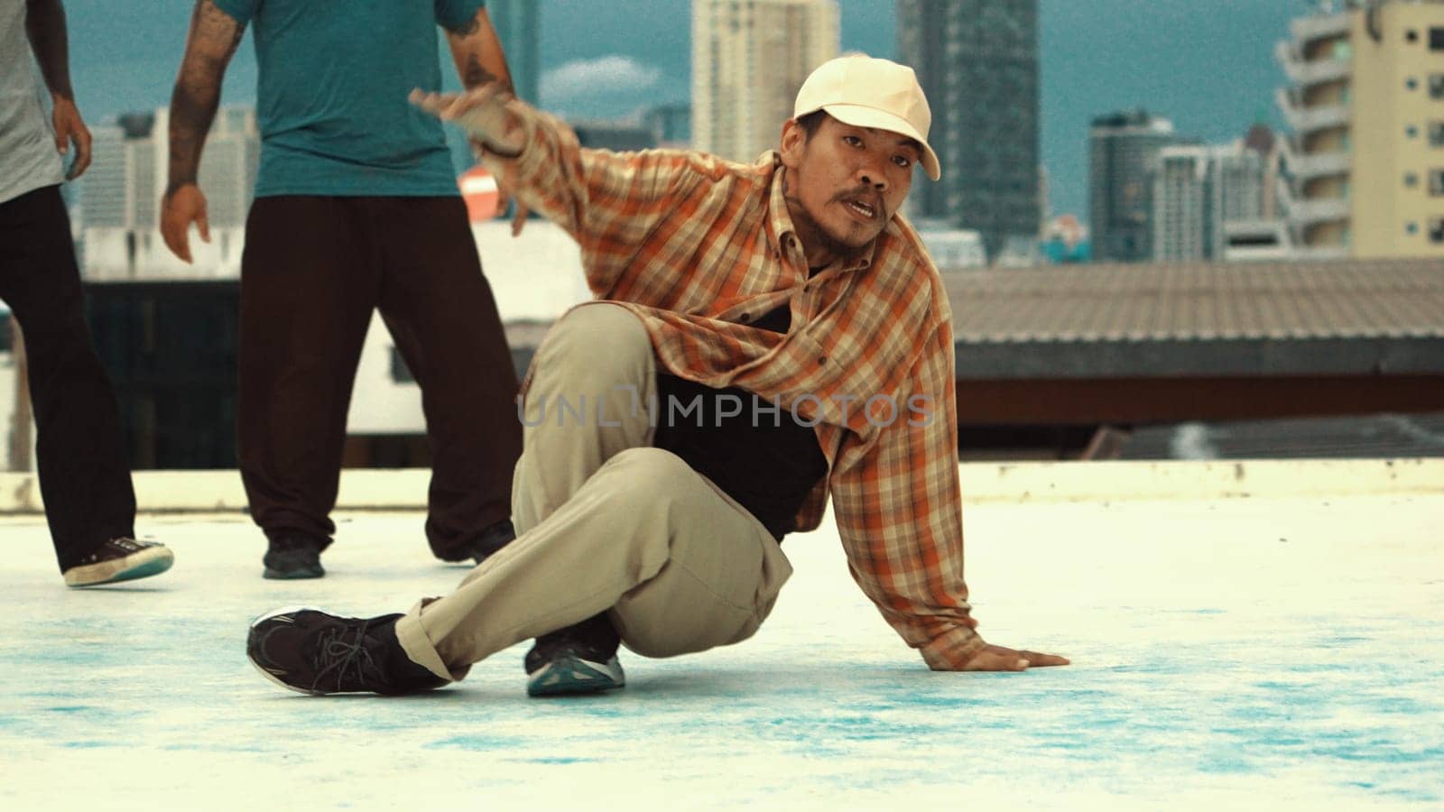 Motion shot of skilled hipster doing break dance at sky scrapper. Professional break dancer or choreographer practicing street dance at rooftop. Outdoor sport 2024. Active, energetic dance. Endeavor.