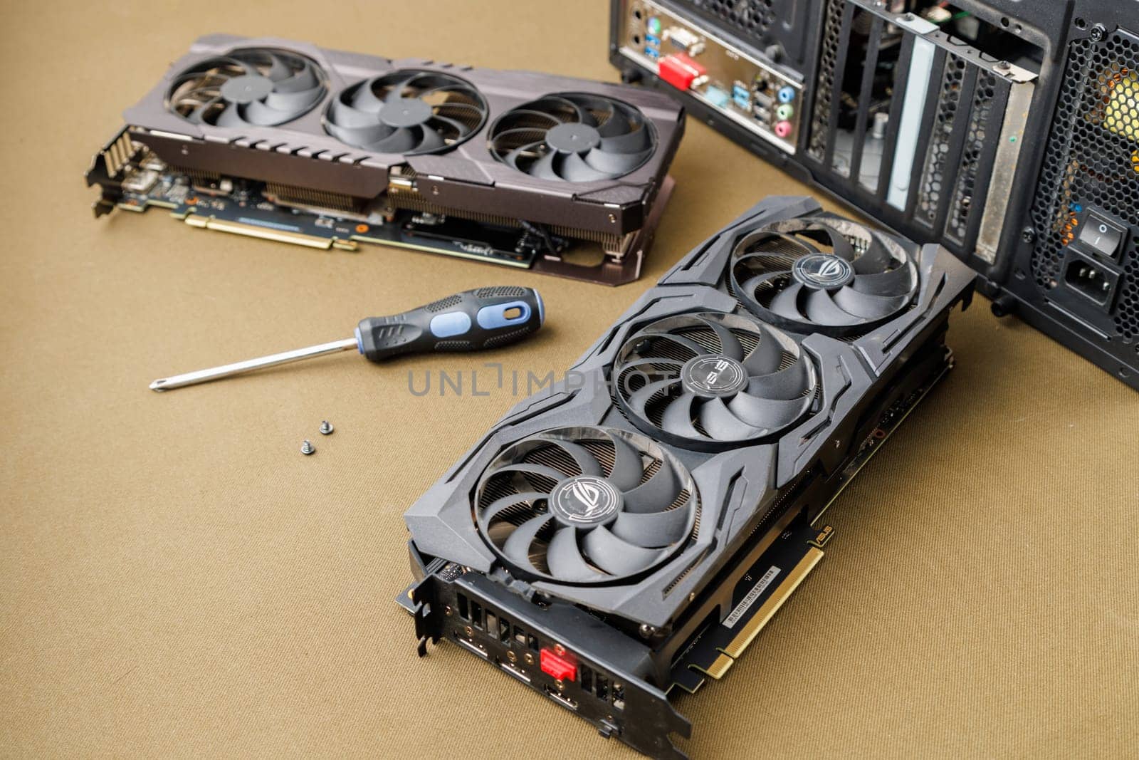 graphics card upgrading concept, two gaming graphics cards near desktop miditower ATX pc case on tan fabric background in Tula, Russia - July 27, 2022