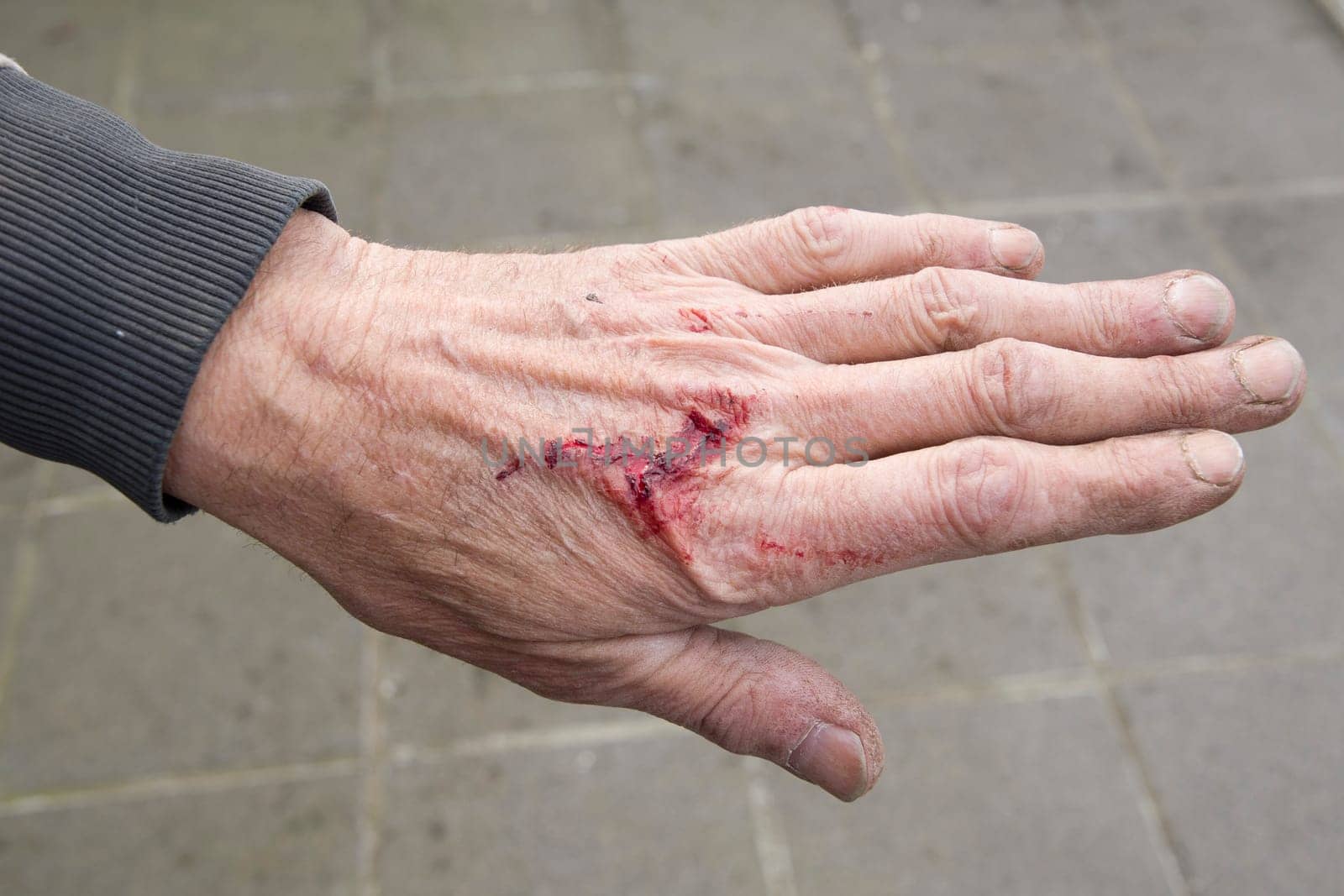 bloody and dirty hands of a working man from the back, male worker with a wound from which blood flows, failure to observe safety precautions when working in the garden, High quality photo
