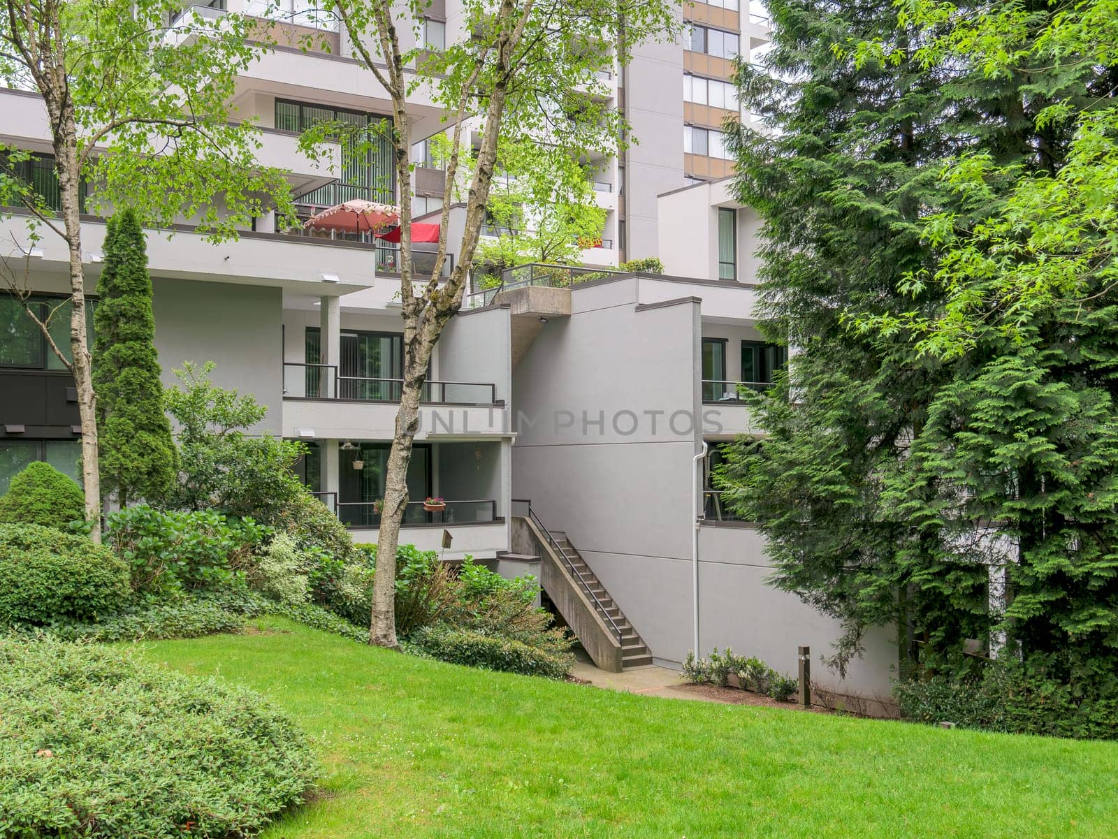 Complex of residential buildings with green lawn and trees in front.