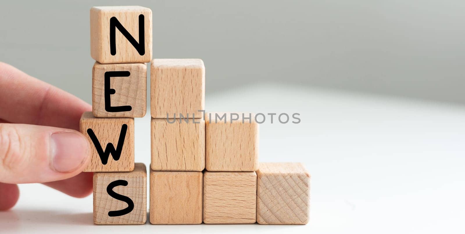 word News on wooden cubes, gray background. Reflection on the mirrored surface of the table. Selective focus. High quality photo