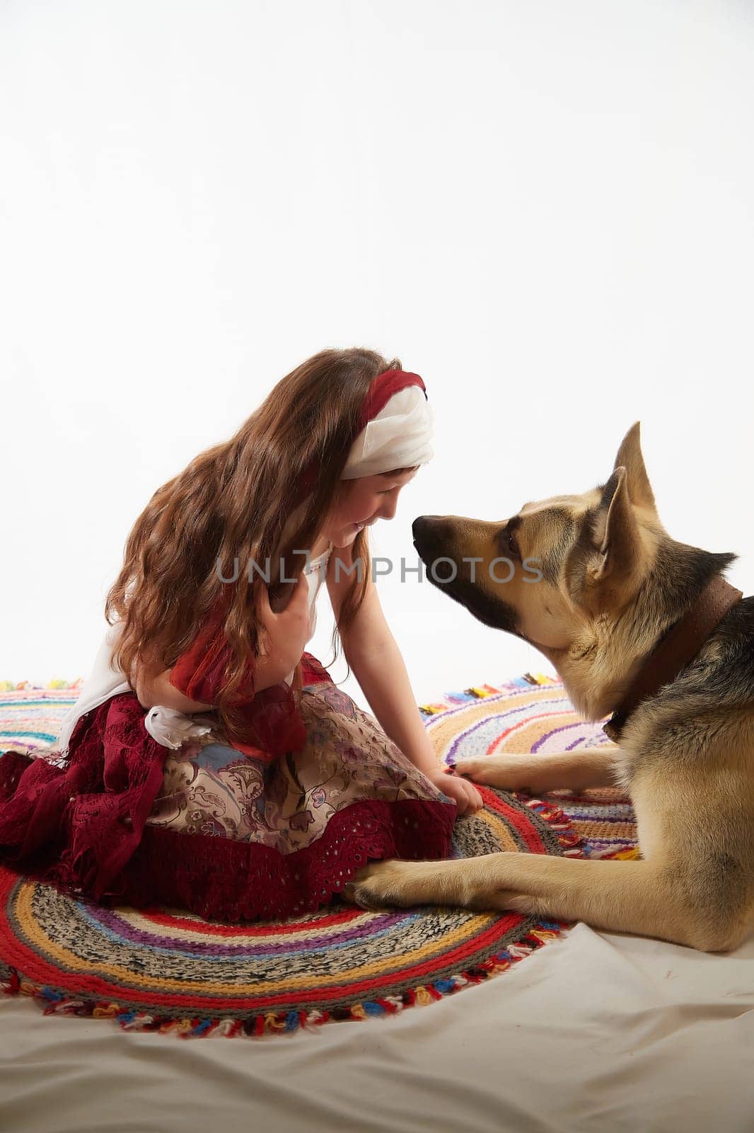 Portrait of Little girl in a stylized Tatar national costume with big shepherd dog on a white background in the studio. Photo shoot of funny young teenager who is not a professional model
