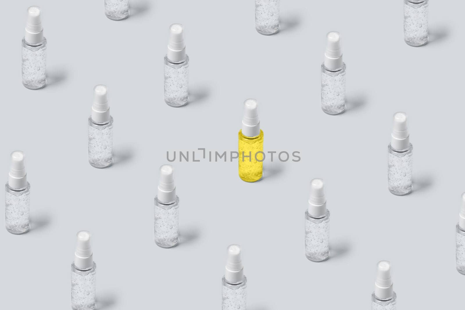 Pattern of bottles with gray and yellow filling on gray background. Advertising cosmetics in the trendy colors of the new year.