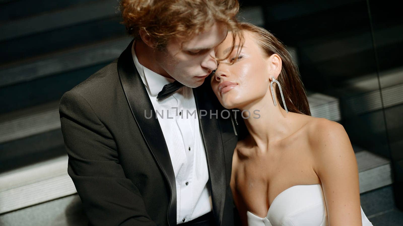 Photo shoot of the bride and groom. Action.The newlyweds are photographed in different places,some posing in the park on the street under the sun,the second on the white staircase,looking at each other tenderly. by Mediawhalestock