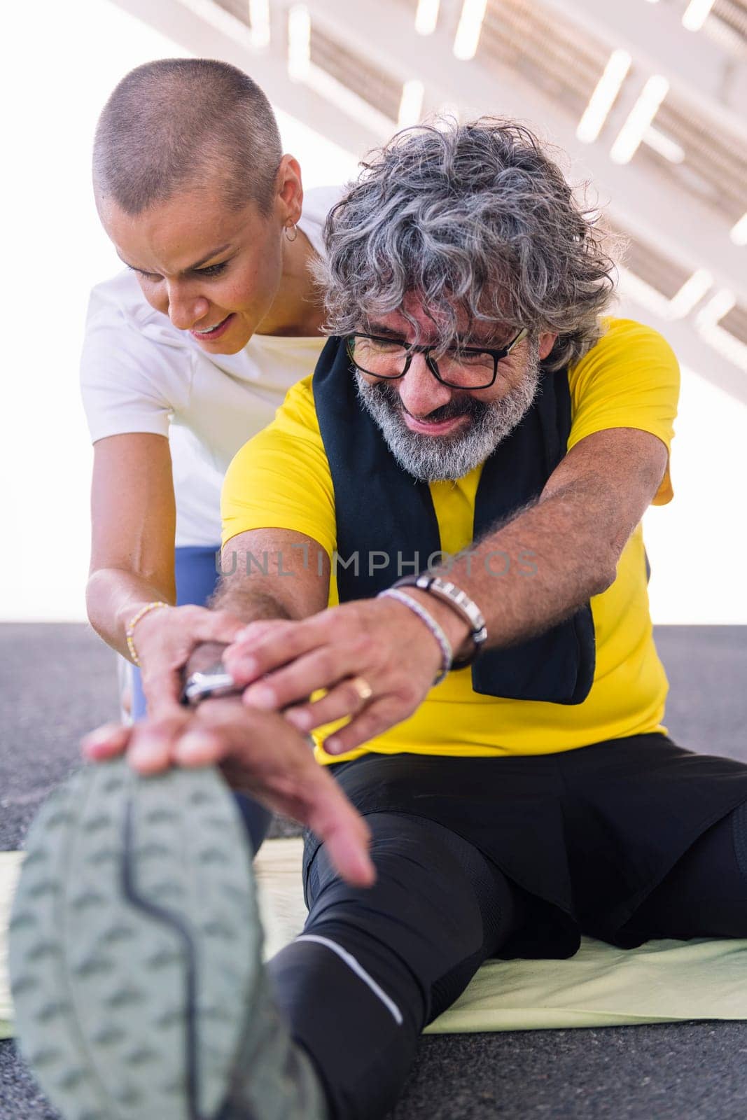 senior sports man stretching legs with his personal trainer, concept of active and healthy lifestyle in middle age