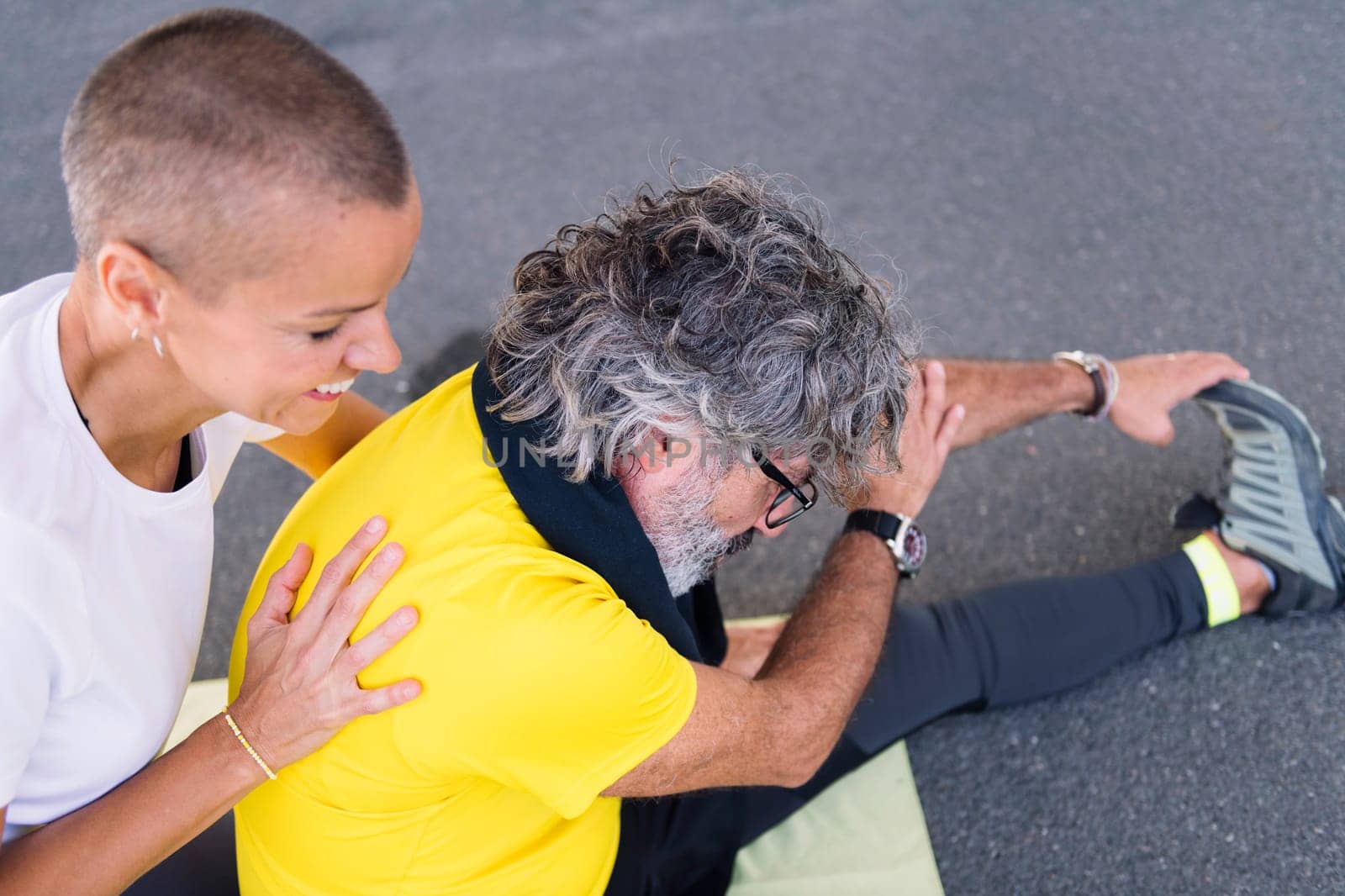 senior sports man stretching legs with help of his personal trainer, concept of active and healthy lifestyle in middle age