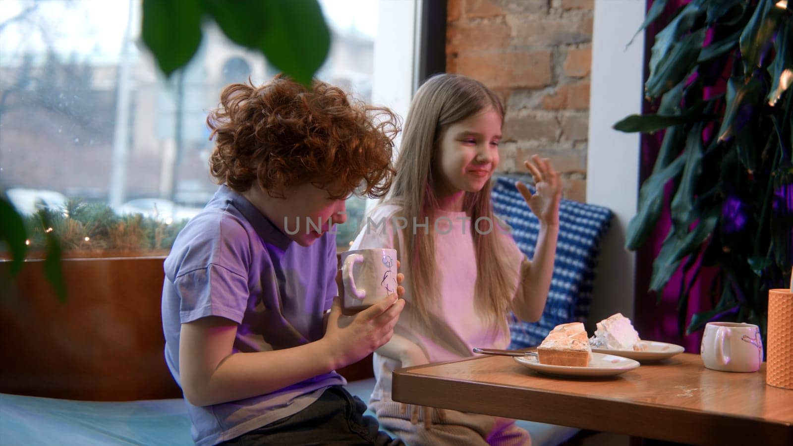 Kids playing with a dog toy at a table cafe. Stock footage. Children having fun and holding a puppy toy