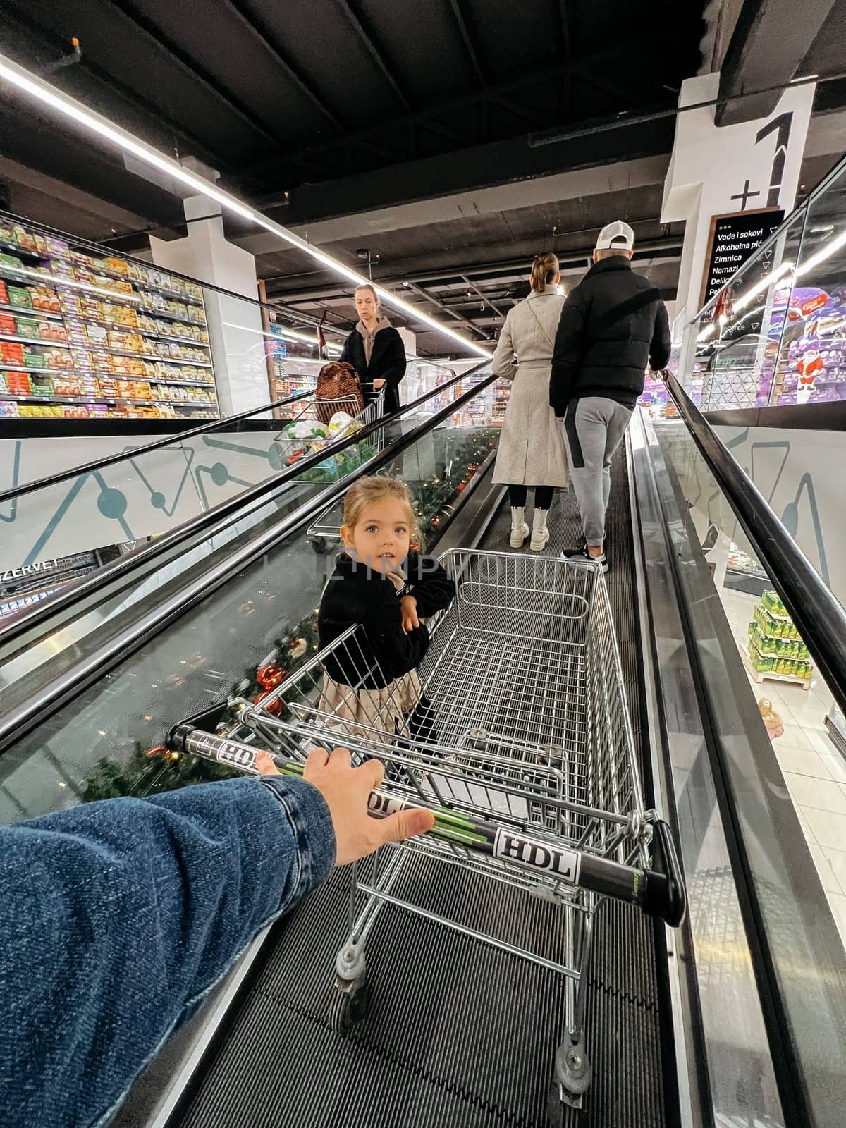 Dad with a little girl ride an escalator in a shopping mall with a shopping cart. High quality photo