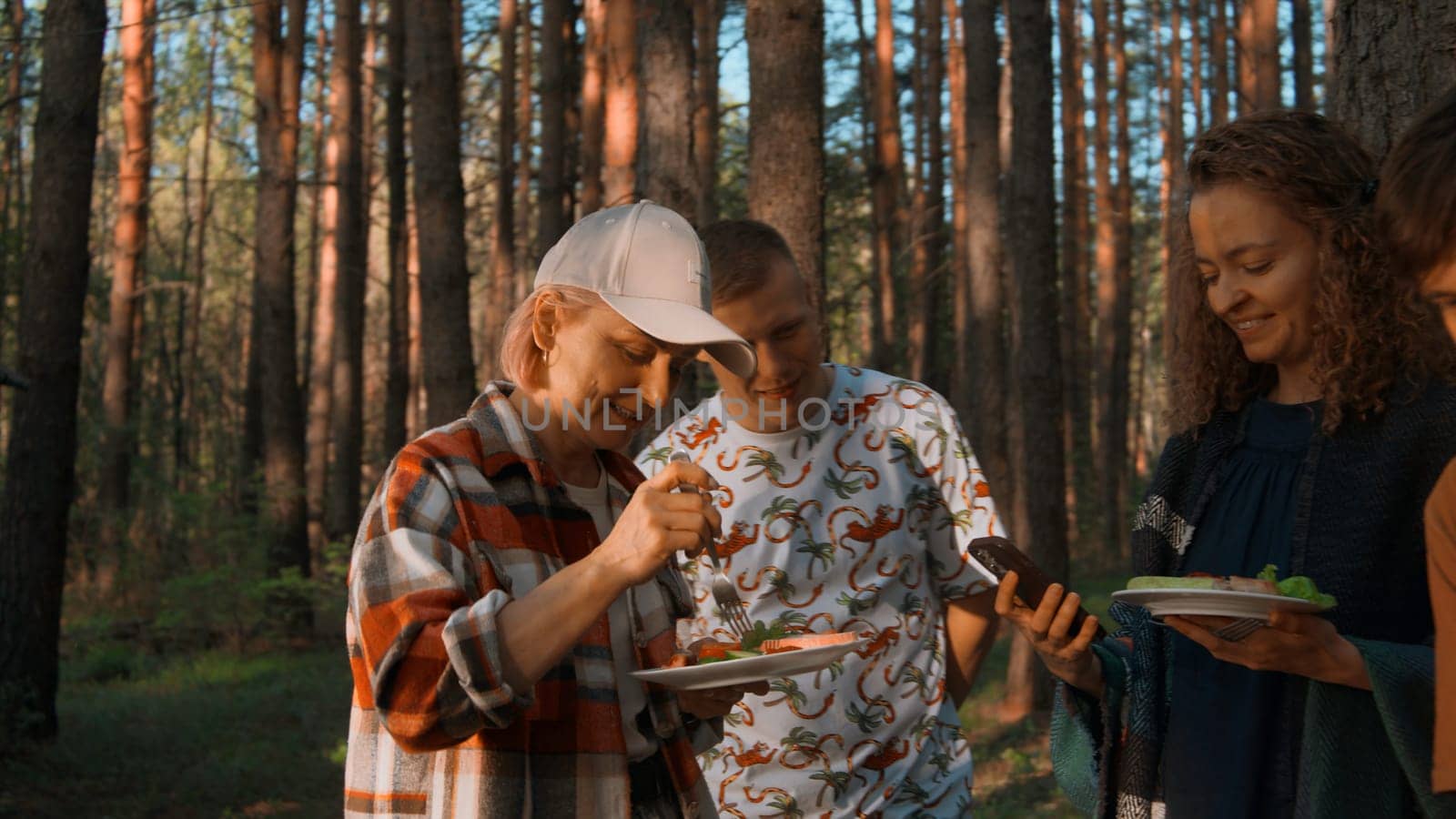 Adult group of friends camping and having a barbecue. Stock footage. Spending time outdoors in summer forest