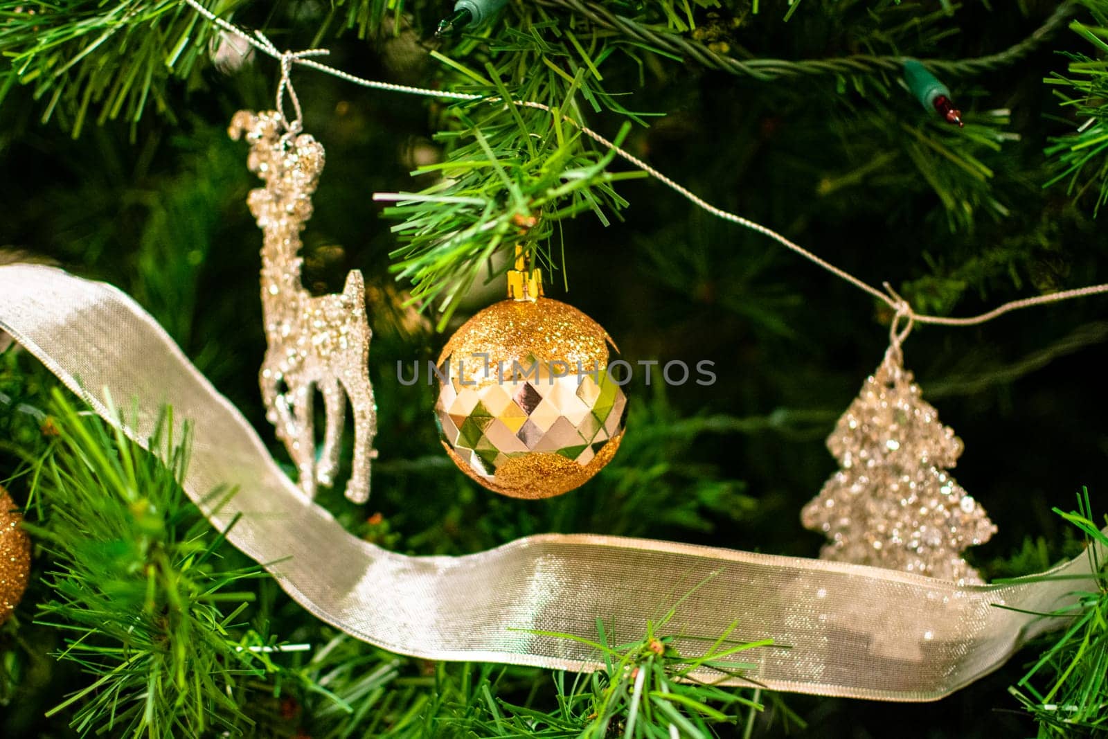 Golden bauble among chistmas tree brenches. Closeup look christmas tree decorations.