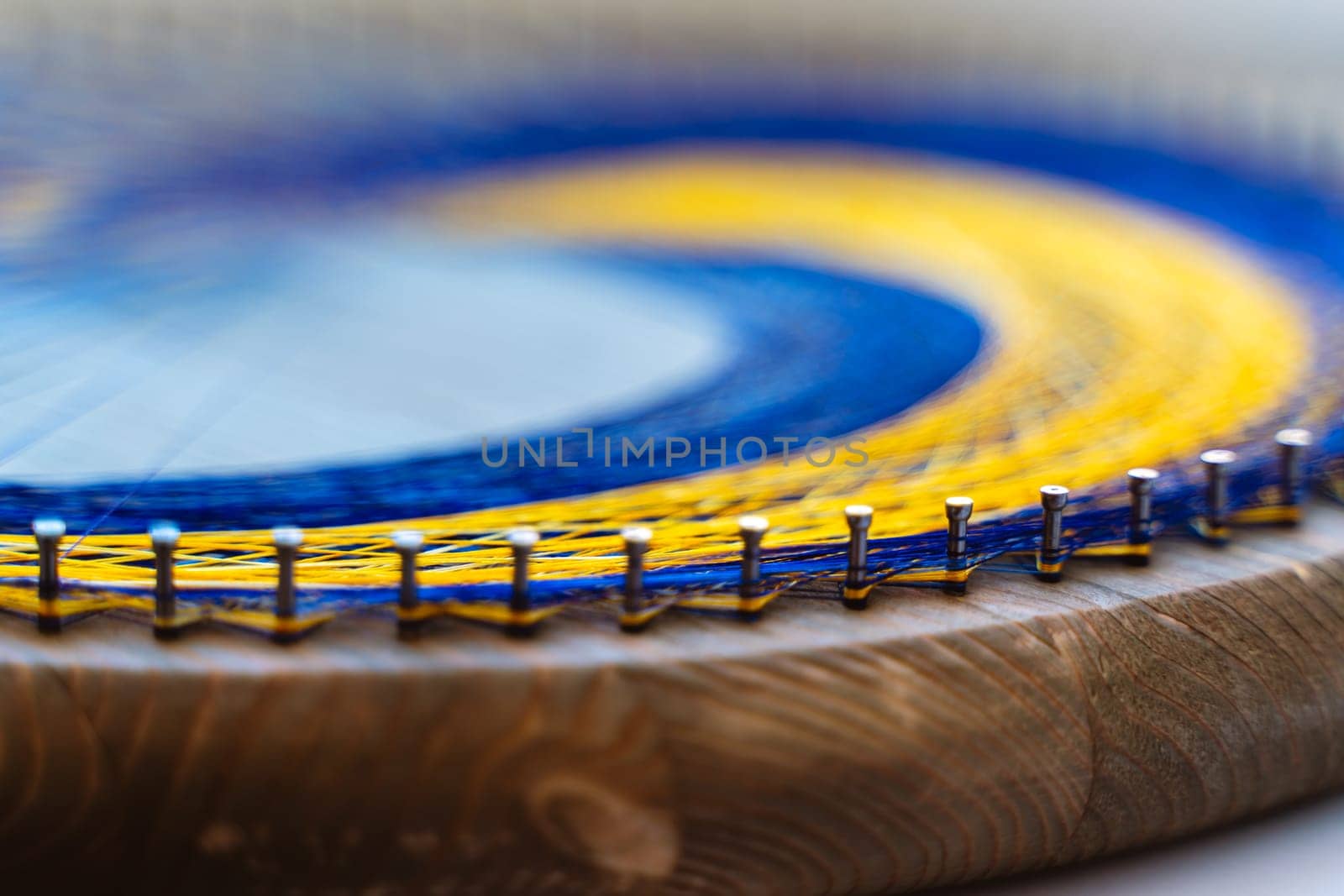 Colored thread mandala on a wooden board with nails. Mandala Moon Harmony Sun esotericism and psychology pictures from yellow and blue silk threads