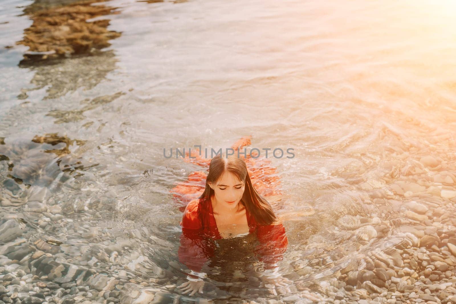 Woman travel sea. Happy tourist in red dress enjoy taking picture outdoors for memories. Woman traveler posing in sea beach, surrounded by volcanic mountains, sharing travel adventure journey by panophotograph