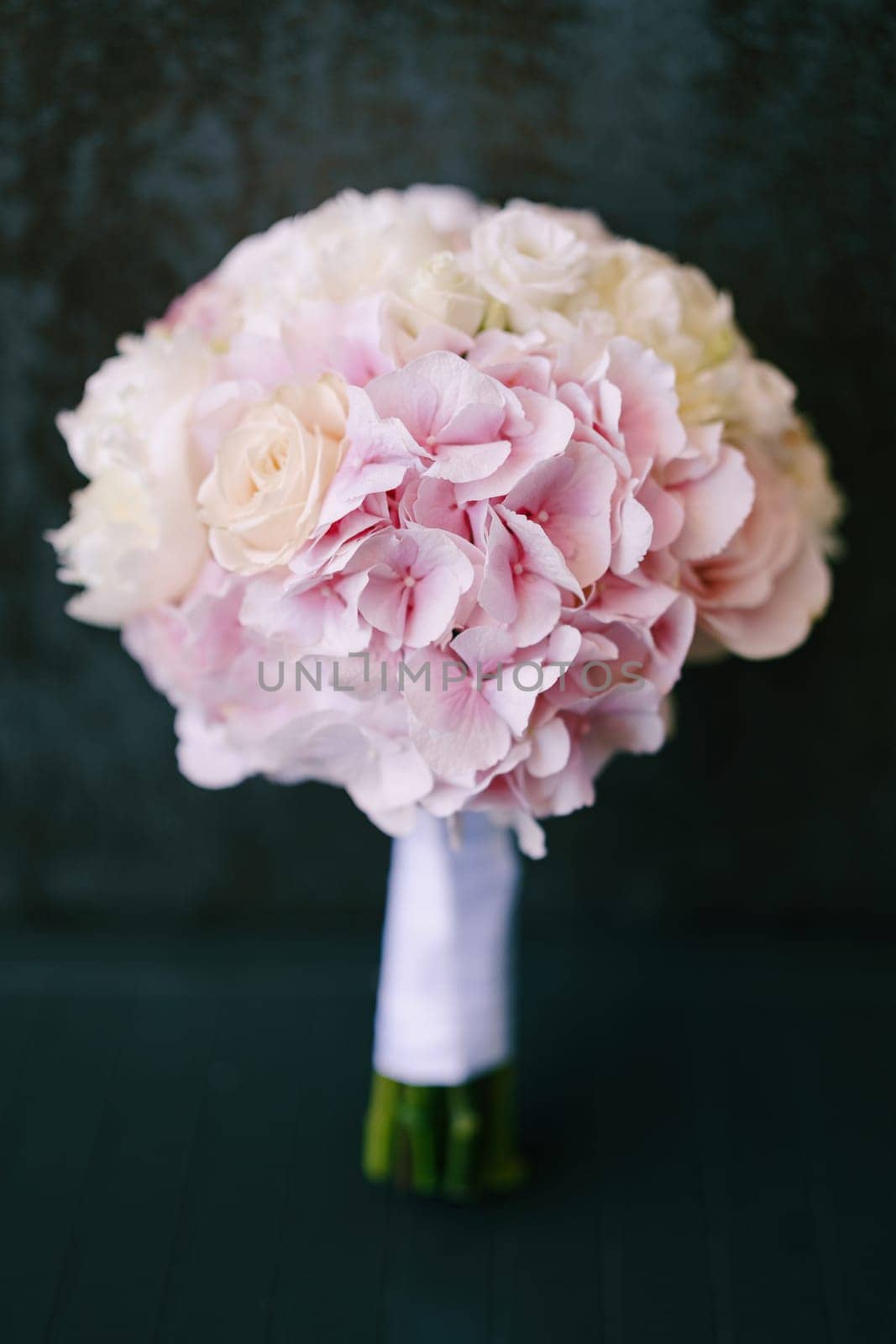 Bridal pink bouquet stands on the floor against the wall by Nadtochiy
