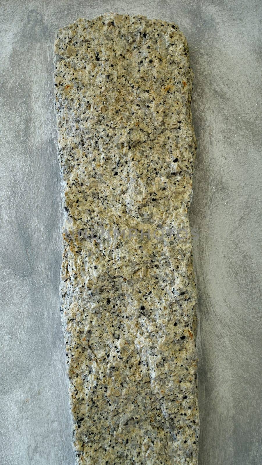 A granite pillar protrudes from a reinforced concrete wall of a building.