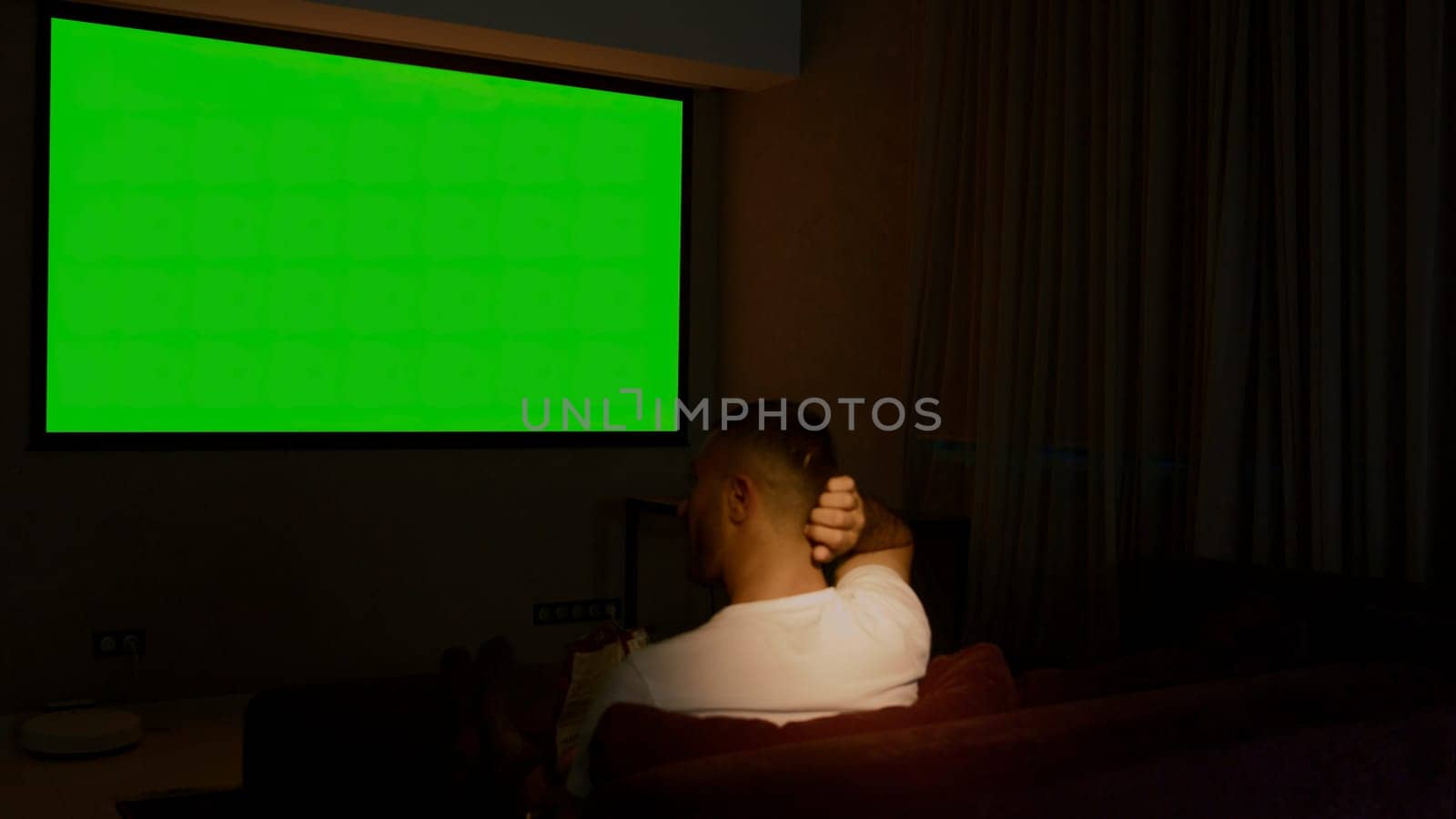 Viewing on a projector in a closed room. Media. A man looking into a green screen that is shown on a large screen. High quality 4k footage